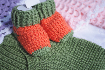Handmade knitted baby booties on colorful fabrics