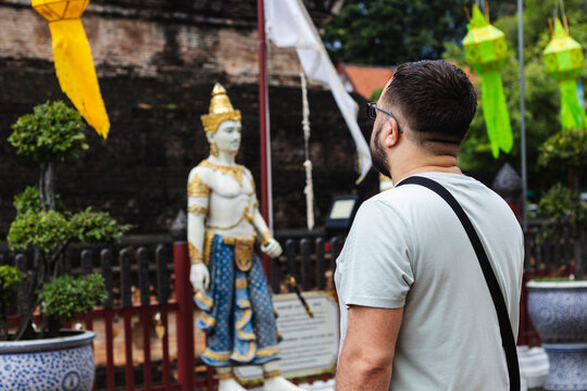 Tourist explores temple, admiring Thai cultural statue