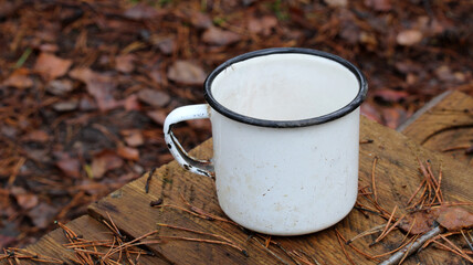 Enamel mug resting on wood plank outdoors