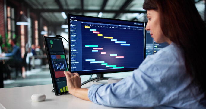 Businesswoman Analyzing Financial Data On Dual Screens