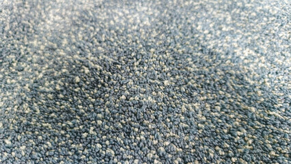Extreme macro view of a blue and gray speckled carpet or rug texture with a shallow depth of field. Abstract and grainy background for textile, fabric, or flooring concepts