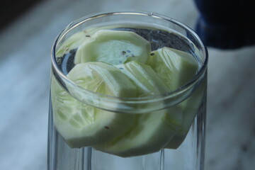 Healthy smoothie with cucumber pieces chopped into it. Health drink with green chopped fruit on a glass.