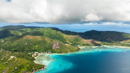 Lush green hills meet white sandy beaches and clear turquoise waters. Curieuse, Seychelles.