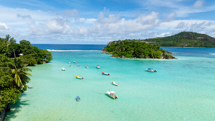 Small boats anchored on a turquoise lagoon with lush greenery surrounding the calm waters....