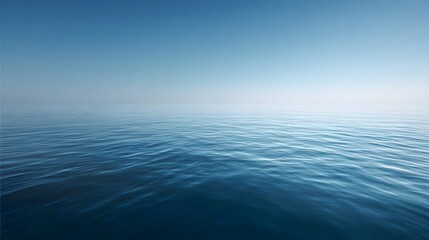 Obraz premium Expansive blue water surface meets a clear, pale sky at the horizon line