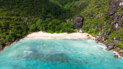 Lush hills frame a secluded, crystal clear beach. Seychelles. Anse Du Riz beach. Baie Ternay Marine National Park.
