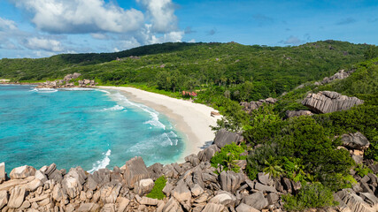 Fototapeta premium A turquoise beach surrounded by lush greenery and large rocky formations. Grand Anse Beach, La Digue, Seychelles.