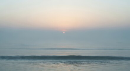 Fototapeta premium Soft pastel sunrise over a calm ocean with gentle wave motion blur