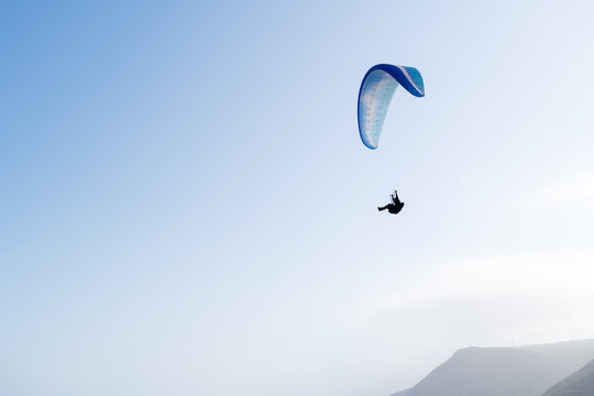 Paragliding against a brilliant sky and coastal mountain range