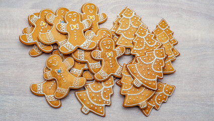 Delicious gingerbread men and Christmas trees on a wooden surface