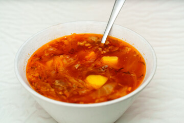 Bowl of comforting borscht awaits on a bright white table, reflecting the vibrant colors of the delicious soup