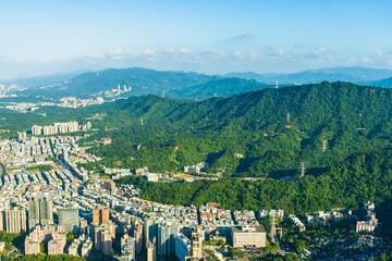 Aerial view of a city bordering lush green mountains under a blue sky