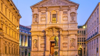 Ornate baroque church facade illuminated at dusk in european city