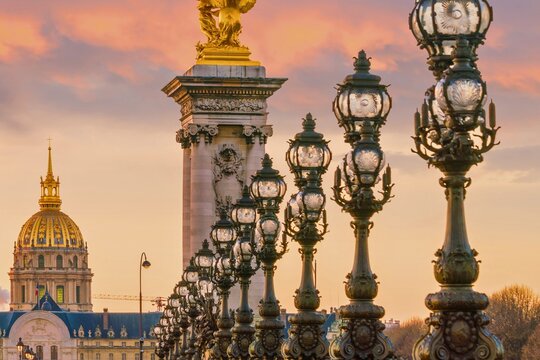 Ornate streetlamps on a parisian bridge with golden dome in background
