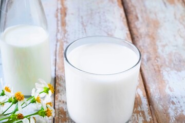 Fresh milk in a glass with flowers on a wooden table