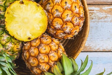 Freshly cut pineapple halves and whole fruits in a basket