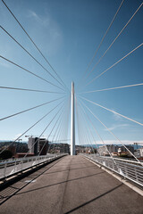 Modern cable-stayed bridge with clean geometric lines against a clear blue sky, ideal for architecture and infrastructure concepts