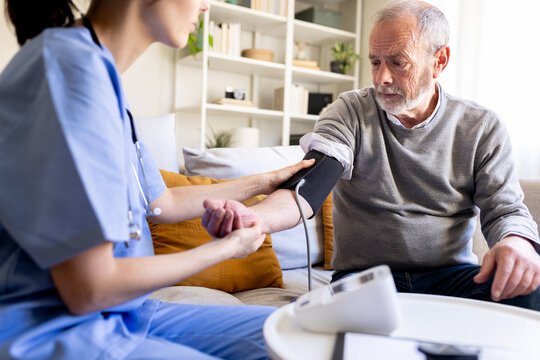 Nurse measuring blood pressure of senior man at home