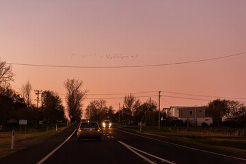 dusk sky above road with car traveling onward and powerlines overhead