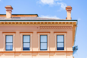 second story windows in creamy pink historic building in country town of Glen Innes