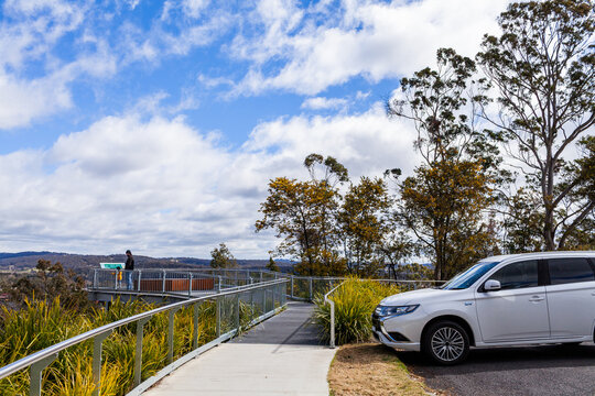 Car parked at Glen Innes Highlands Skywalk with tourists walking by on windy winter day