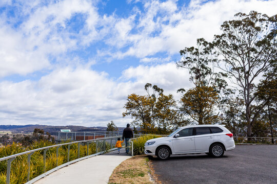 Car parked at Glen Innes Highlands Skywalk with tourists walking by on windy winter day