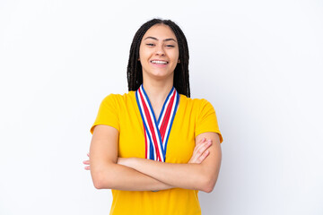 Teenager girl with braids and medals over isolated pink background keeping the arms crossed in...