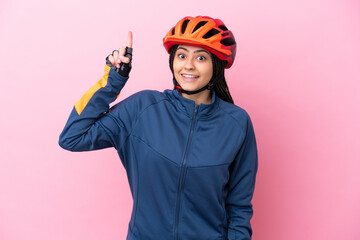 Teenager cyclist girl isolated on pink background pointing up a great idea