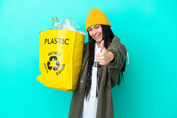 Teenager girl with braids holding a bag to recycle with thumbs up because something good has...