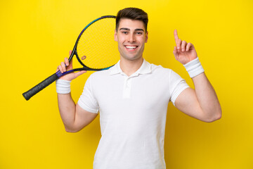 Young caucasian man isolated on white background playing tennis and pointing up