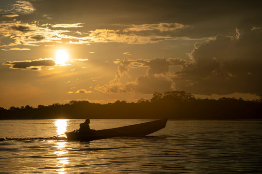 wooden boat in amazon river at sunset