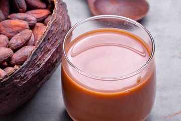 Freshly made chocolate drink next to cacao pods and beans