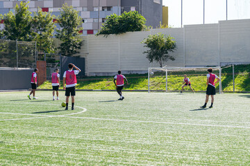 Young male athletes practicing football on an urban turf field, focusing on skill development and team sport