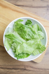 Iceberg salad in a bowl on the table, salad preparation. Iceberg Lettuce in a Bowl on Cutting Board