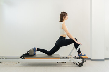 Naklejka premium ピラティス女子 日本人女性がリフォーマーでポーズ