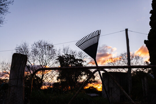 silhouette of rake on farm gate at dusk