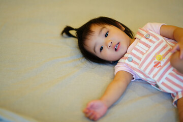 Smiling Baby Lying on Bed in Yellow Onesie