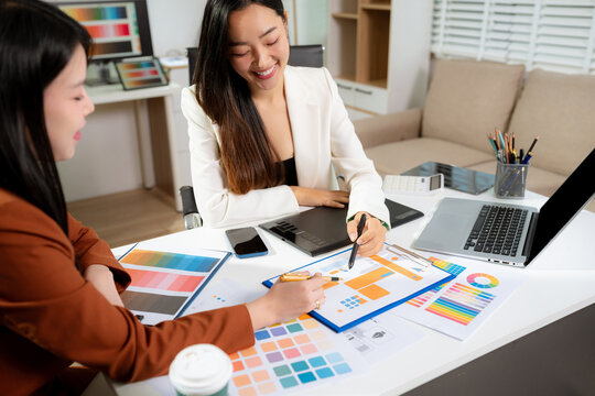 Stylish woman designer working with digital tablet and laptop in a bright studio. - Powered by Adobe