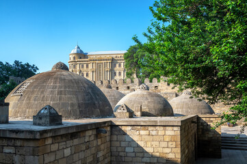 Exterior view of an old Turkish bathhouse in Baku Azerbaijan with domed roof and stone walls under a sunny blue sky.
