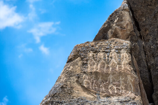 Ancient human figures carved into rock surfaces at the historic petroglyph site of Qobustan, Azerbaijan.