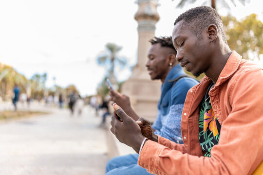 African male friends connecting with smartphones outdoors in a park