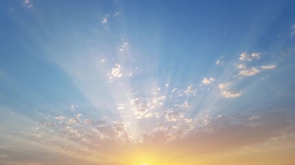 Wide view of a vibrant sunrise over the horizon with soft clouds golden rays breaking through the clear blue sky showcasing the transition of light from dawn to daytime. - Powered by Adobe