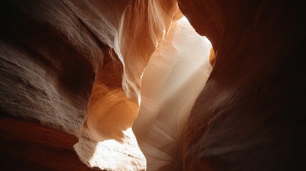 Close-up of a narrow slot canyon with a light shining through it. the canyon walls are made up of different shades of brown and beige, with some areas appearing to be eroded and eroded.