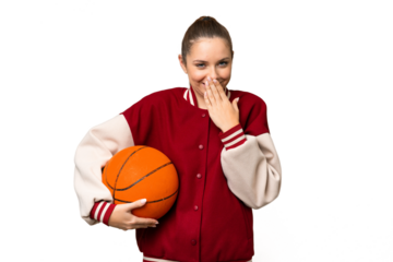 Young blonde woman playing basketball over isolated chroma key background happy and smiling covering mouth with hand