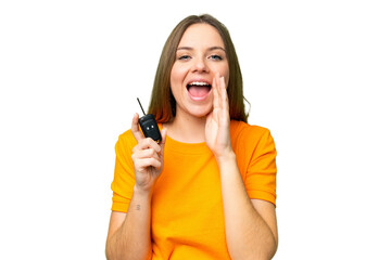 Young woman holding car keys over isolated chroma key background shouting with mouth wide open