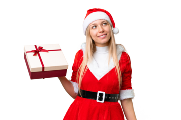 Young blonde woman with christmas hat and holding a gift over isolated chroma key background looking up while smiling