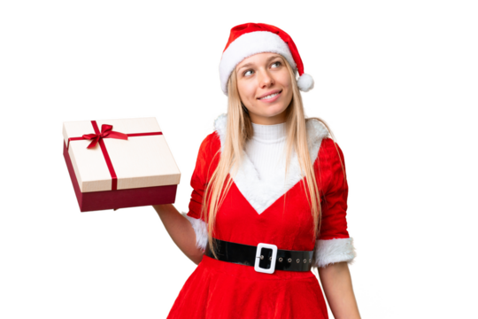 Young blonde woman with christmas hat and holding a gift over isolated chroma key background looking up while smiling - Powered by Adobe