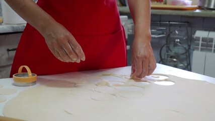 Soft floury dough is held by delicate hands above the white table. The cook checks the small pastry round to prepare delicious homemade dumplings.