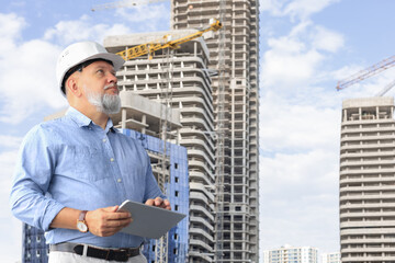 Mature architect wearing hardhat inspecting new building.