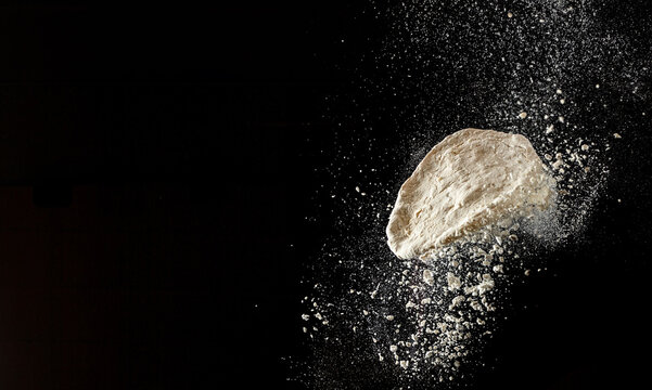 Dynamic flour burst with flying dough on dark background for bakery and cooking advertising